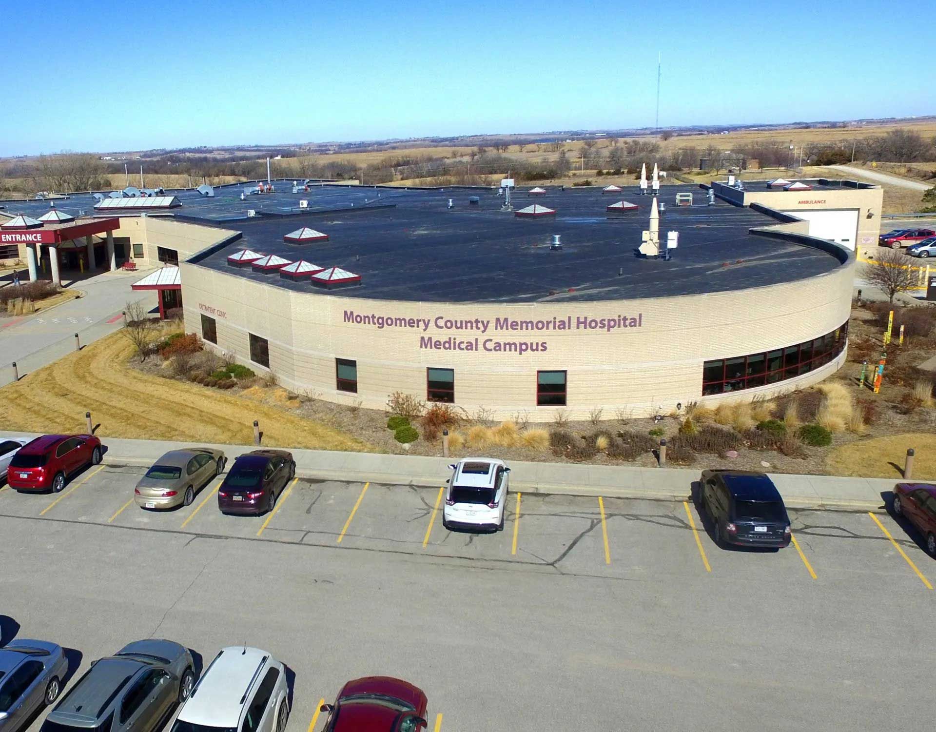 Montgomery County Memorial Hospital building with parked cars, sunny day.