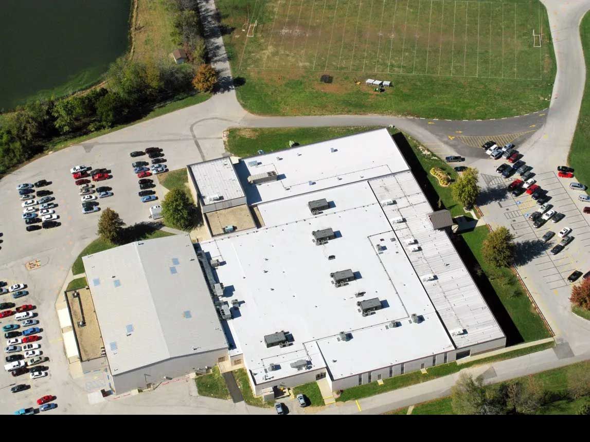 Aerial view of a large commercial building with multiple white roof sections