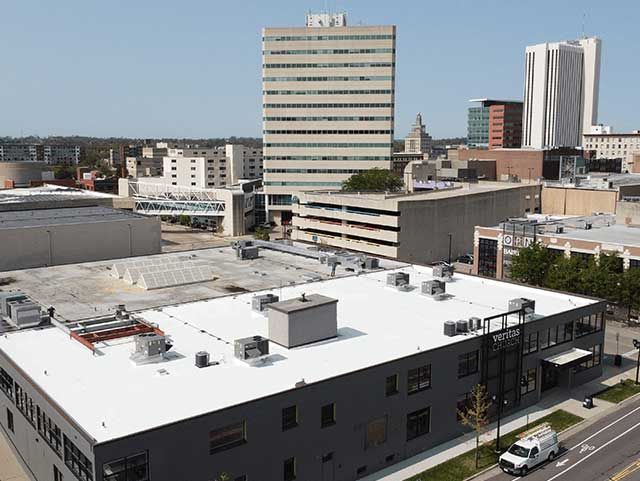 City skyline with office buildings and a large white roof in foreground.