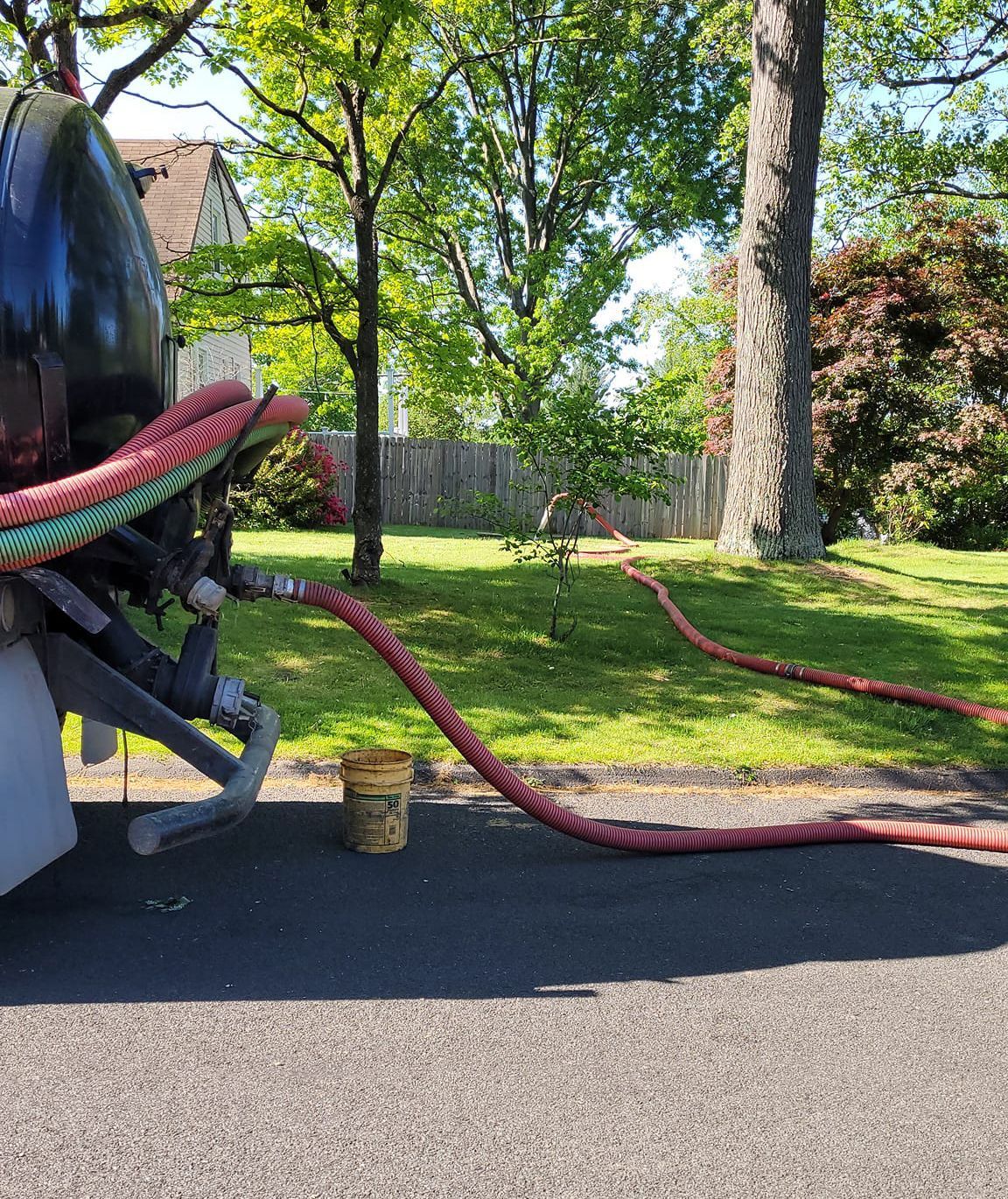 A septic tank is sitting on the side of the road with a hose attached to it.