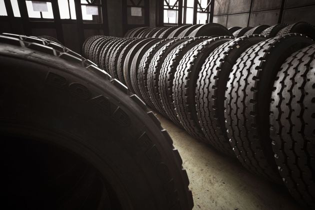 Rows of stacked tires in a dim warehouse, with a large tire in the foreground.