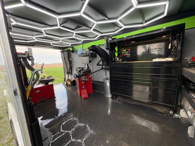 Modern garage interior with hexagonal LED ceiling lights, black cabinets, and a vehicle lift.