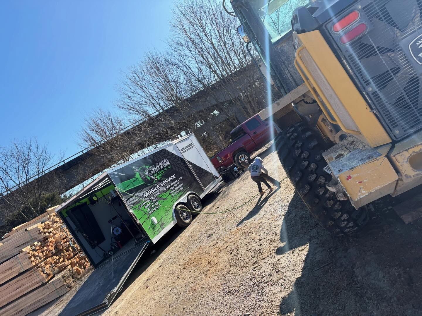 Construction equipment at a tilted site with a worker walking near a green dumpster and yellow vehicle.