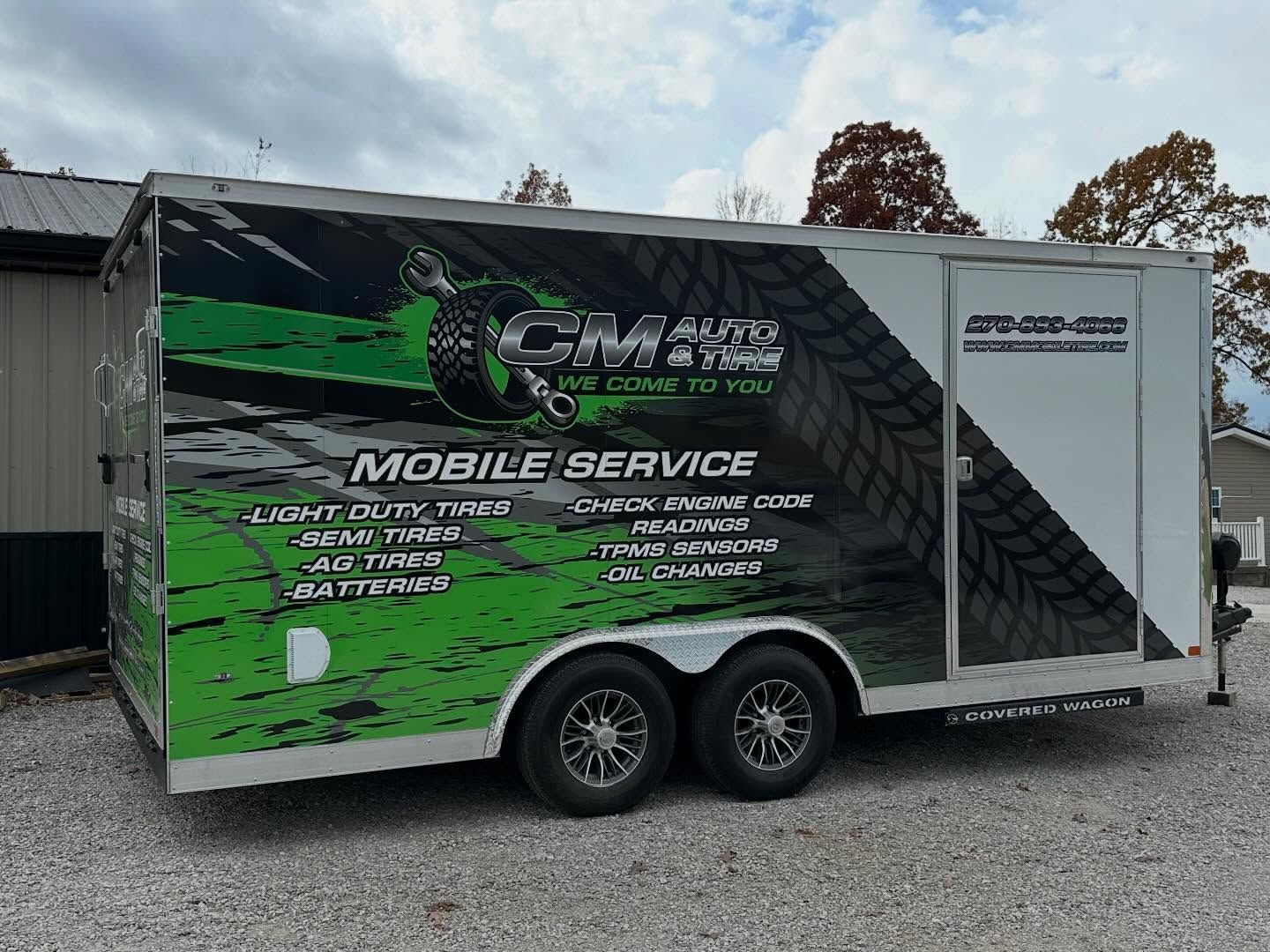 Black-and-green mobile service trailer with company branding parked on gravel outdoors