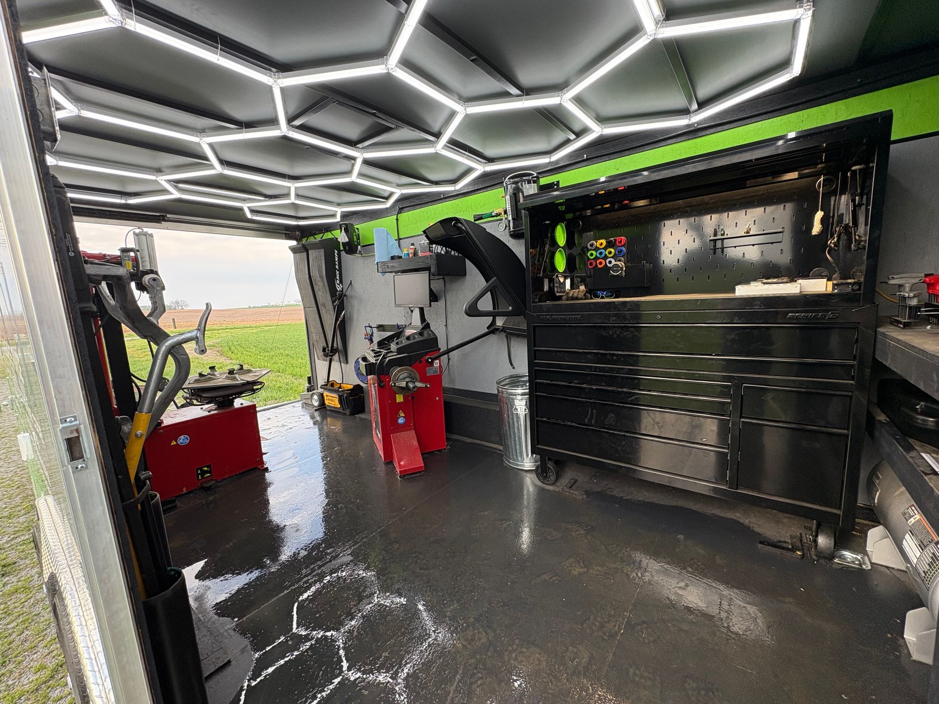 Interior of a custom work van with hexagon LED ceiling lights, tool cabinets, and equipment inside.