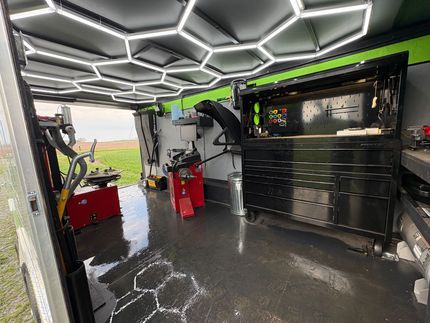 Interior of a custom work van with hexagon LED ceiling lights, tool cabinets, and equipment inside.