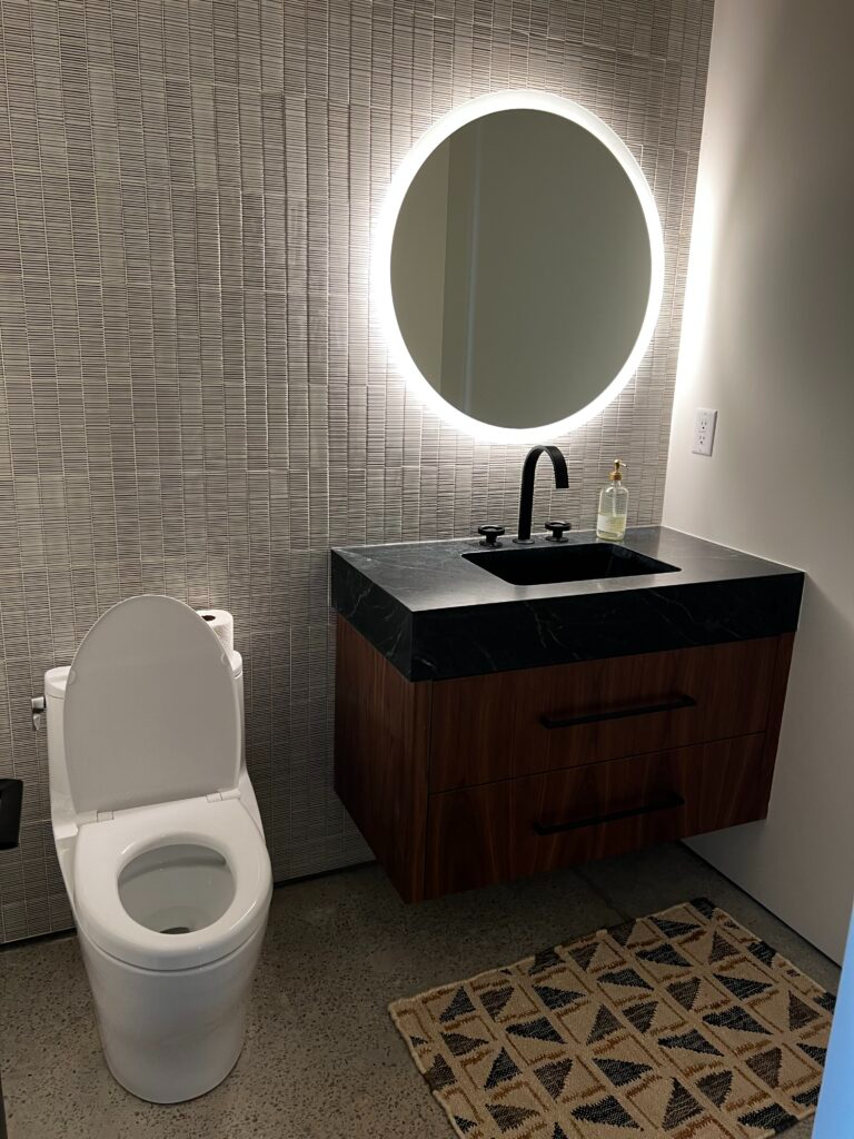 A bathroom with a toilet, sink and mirror.