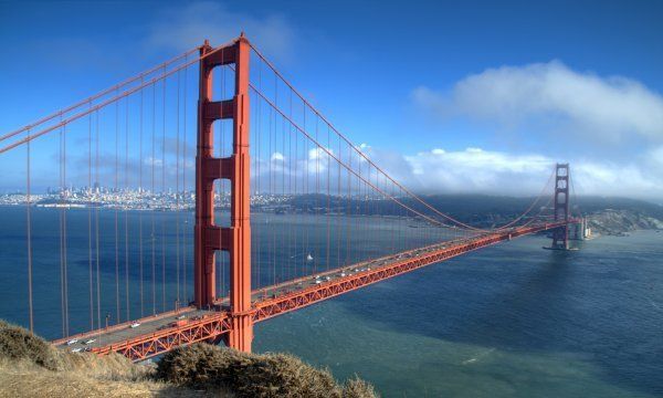 Golden Gate Bridge spanning blue water under a clear sky, with San Francisco in the background