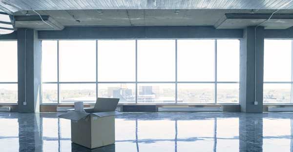 Empty office with large windows, glossy floor, and a single chair near the center