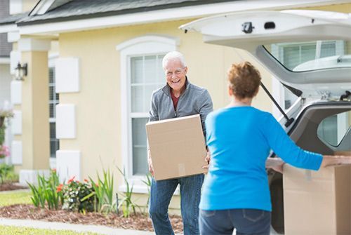 Two people moving a box into a house through an open garage door