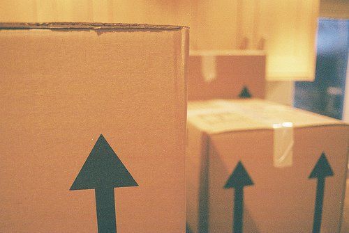 Cardboard moving boxes with green up arrows in a warm indoor setting