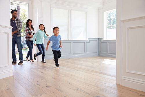 Family walking through a bright empty room with light wood floors and white walls