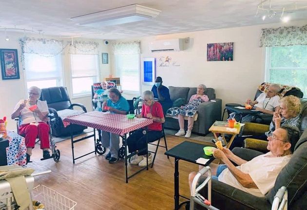 People relaxing in a bright living room, seated around tables and sofas with drinks and snacks