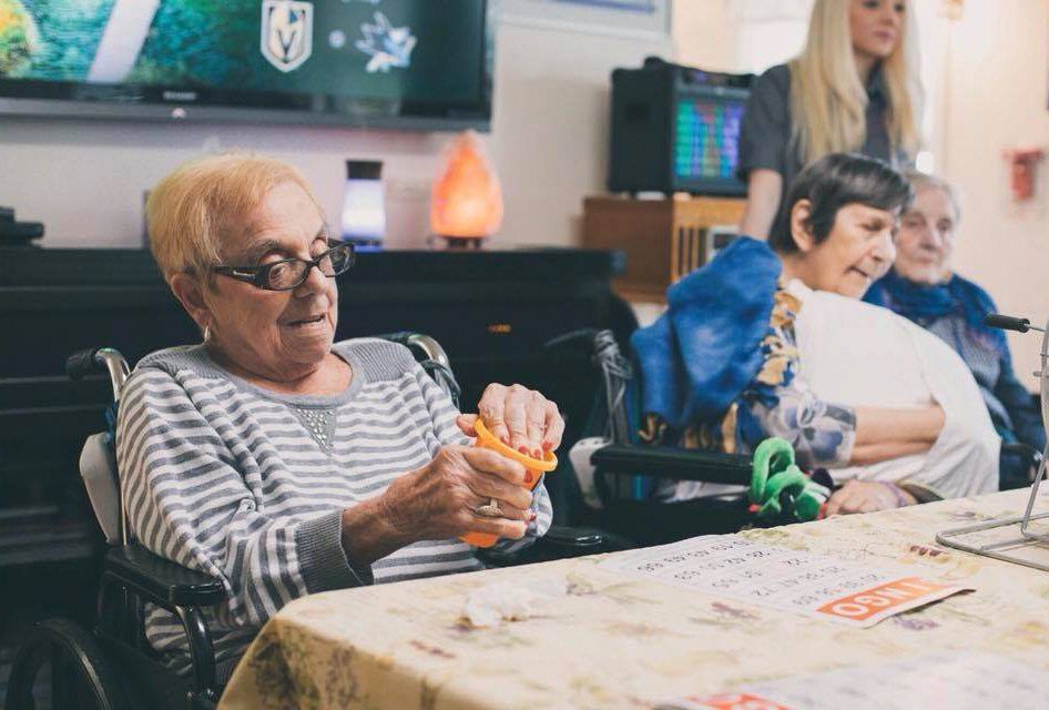 Residents sitting at a table, fidgeting with small objects in a community room