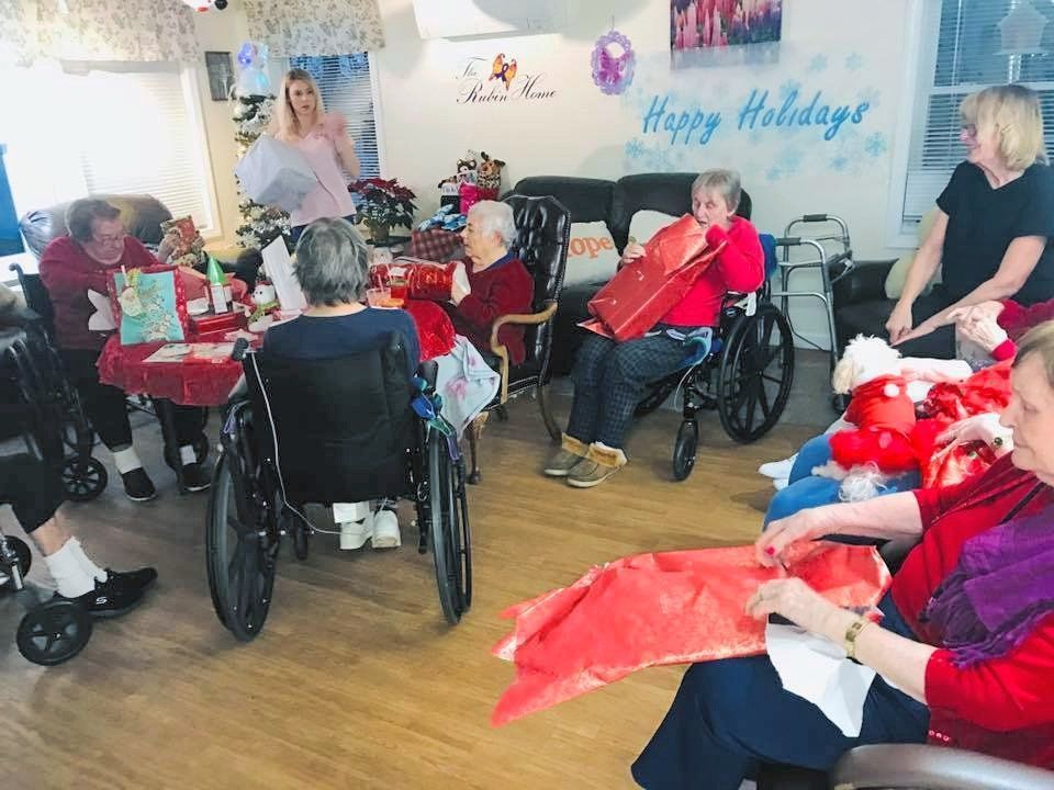 Holiday gathering in a care home, with residents seated in wheelchairs around a decorated room.