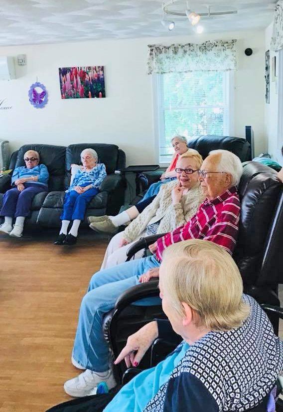 Residents sitting and chatting in a bright living room on black couches and chairs