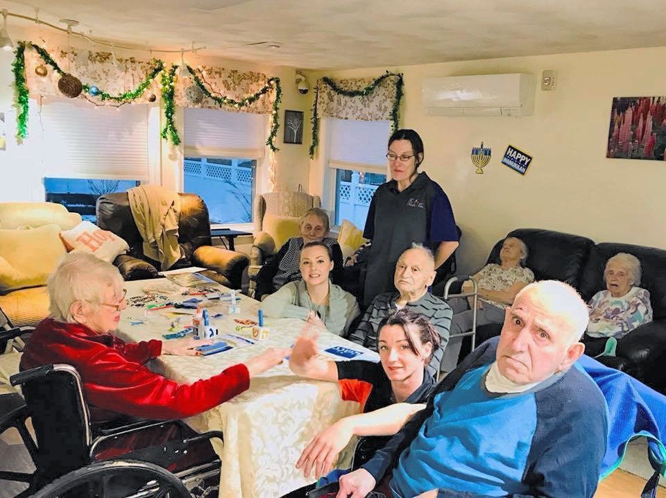 Group of people gathered in a cozy decorated living room, seated around a table and smiling