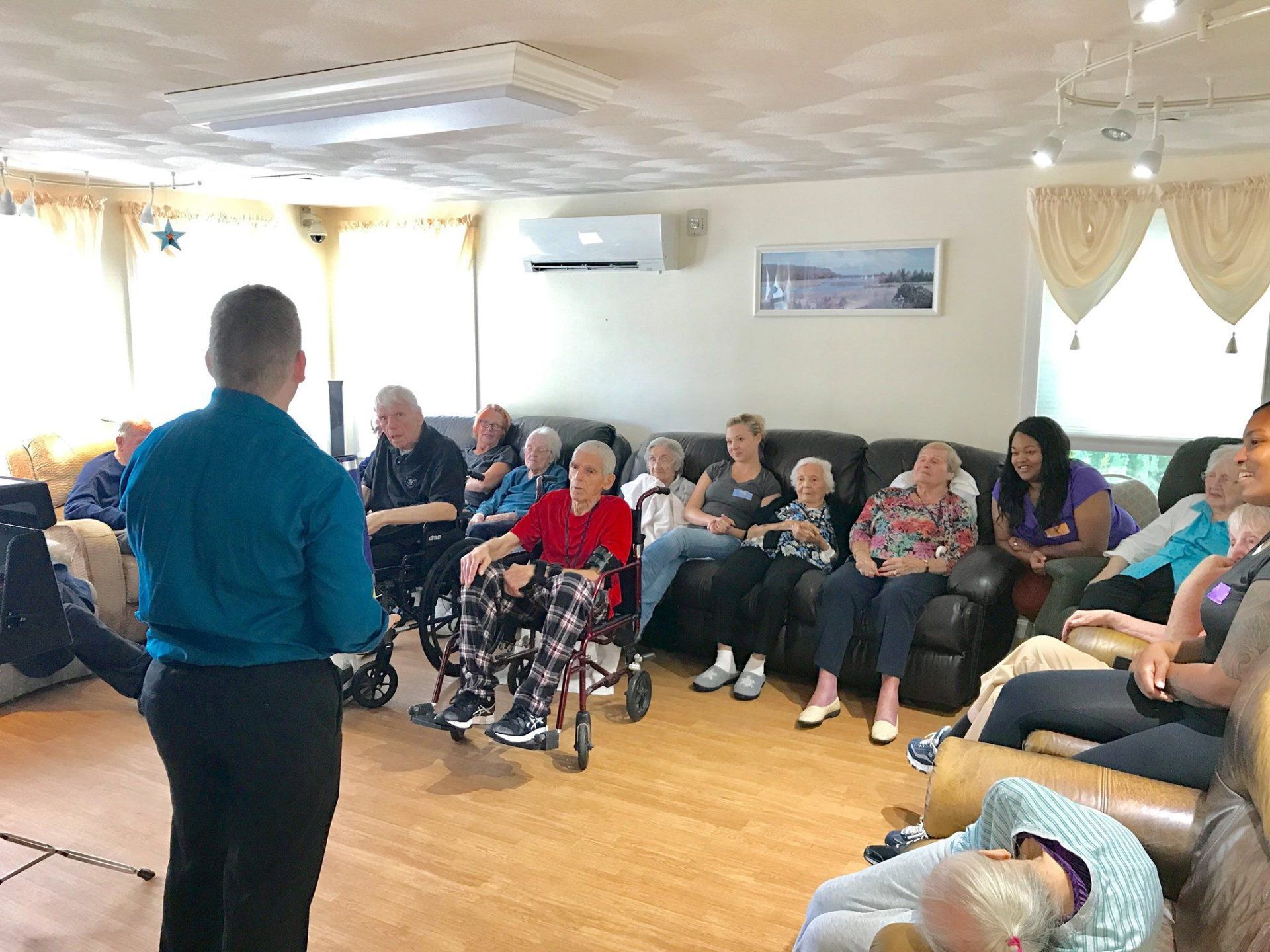 Small group meeting in a living room, with one person speaking to seated attendees.