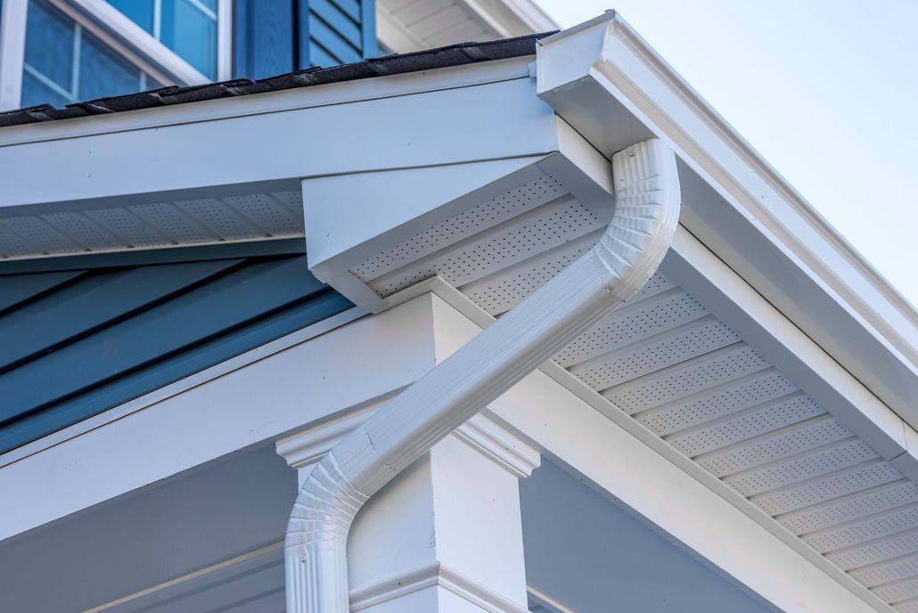 White rain gutter system on a blue and white house exterior.