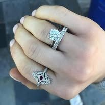 Hand wearing three diamond rings.