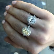 Hand holding two diamond rings, one white, one yellow.