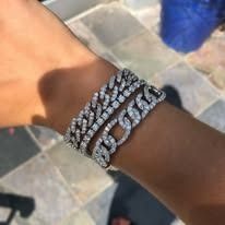 Person's wrist with two diamond-encrusted chain bracelets.