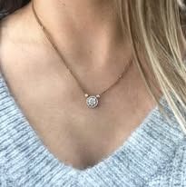 Woman wearing a delicate gold necklace with a diamond pendant, close-up.