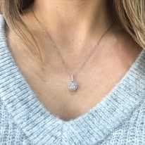 Woman wearing a silver necklace with a small, round diamond pendant.