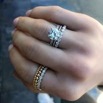 Hand wearing three diamond rings, including a large engagement ring.