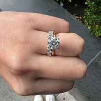 Hand wearing a diamond engagement ring and wedding band.