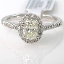 Diamond halo engagement ring, white gold band, oval center stone, surrounded by smaller diamonds.