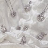 Silver jewelry with sparkling diamonds arranged on white fabric.