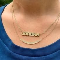 Person wearing a gold necklace with the name 