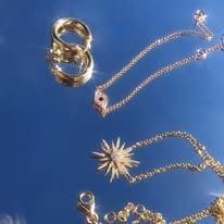 Gold jewelry: rings and necklaces against a blue background.