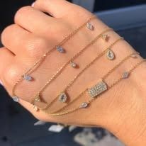 Hand with layered gold necklaces featuring small gemstones.