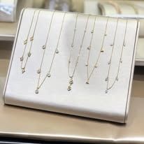 Jewelry display case with several necklaces, all with small pendants, on a light-colored surface.