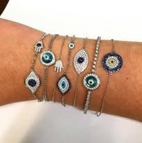 Close-up of a wrist with several beaded bracelets, each with an eye or hand charm.