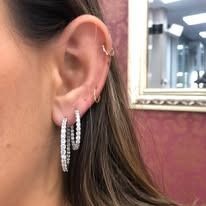 Close-up of a woman's ear with multiple hoop earrings, various sizes, sparkling.