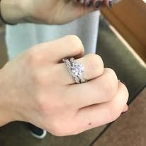 Person's hand with diamond engagement ring and wedding band.