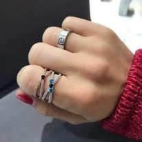 Hand wearing rings, including silver and blue-gem bands.