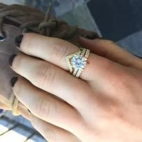 Close-up of a hand wearing a diamond engagement ring with a chevron band.