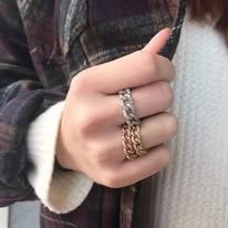 Close-up of hand wearing two chain-link rings. Silver ring on top, gold on bottom.