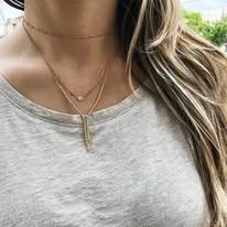 Woman wearing a layered necklace over a gray top.