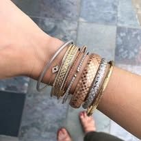 Wrist with multiple gold and silver bracelets.
