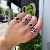 Hand wearing multiple ruby and diamond rings outdoors.
