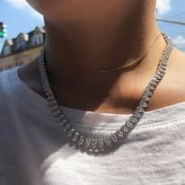 Person wearing a silver diamond necklace, close-up.