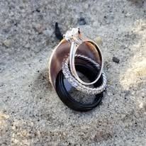Two wedding rings, one black and one silver, stacked on a rock.
