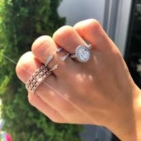 Hand wearing multiple diamond rings, close-up shot.