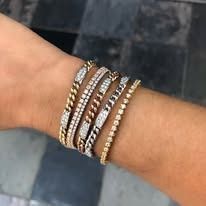 Wrist with multiple gold and diamond bracelets, showing various styles.