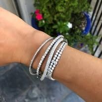 Hand with stack of sparkling diamond bracelets.